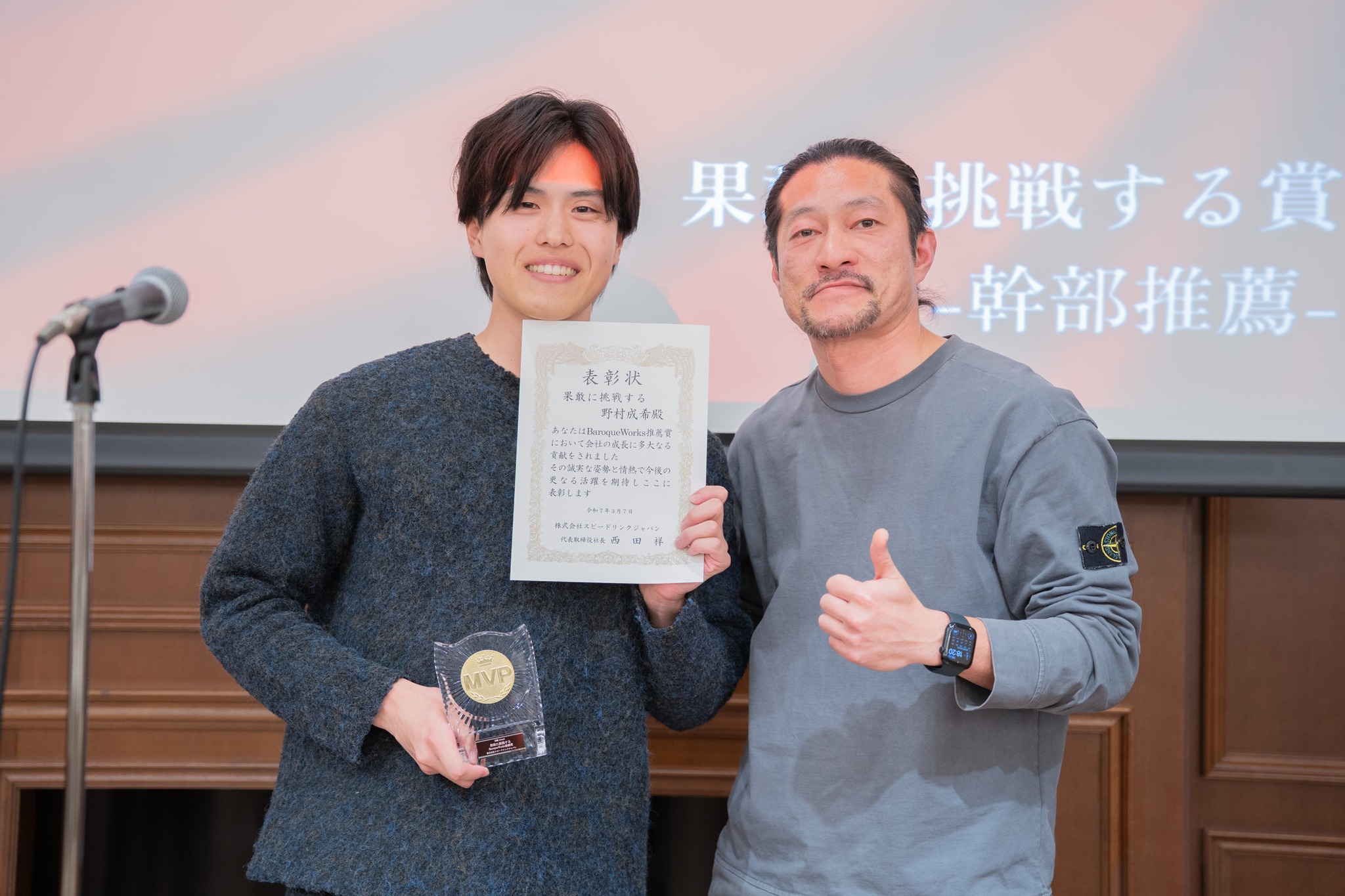 表彰式で社員と代表 西田が並んで笑顔を見せる様子